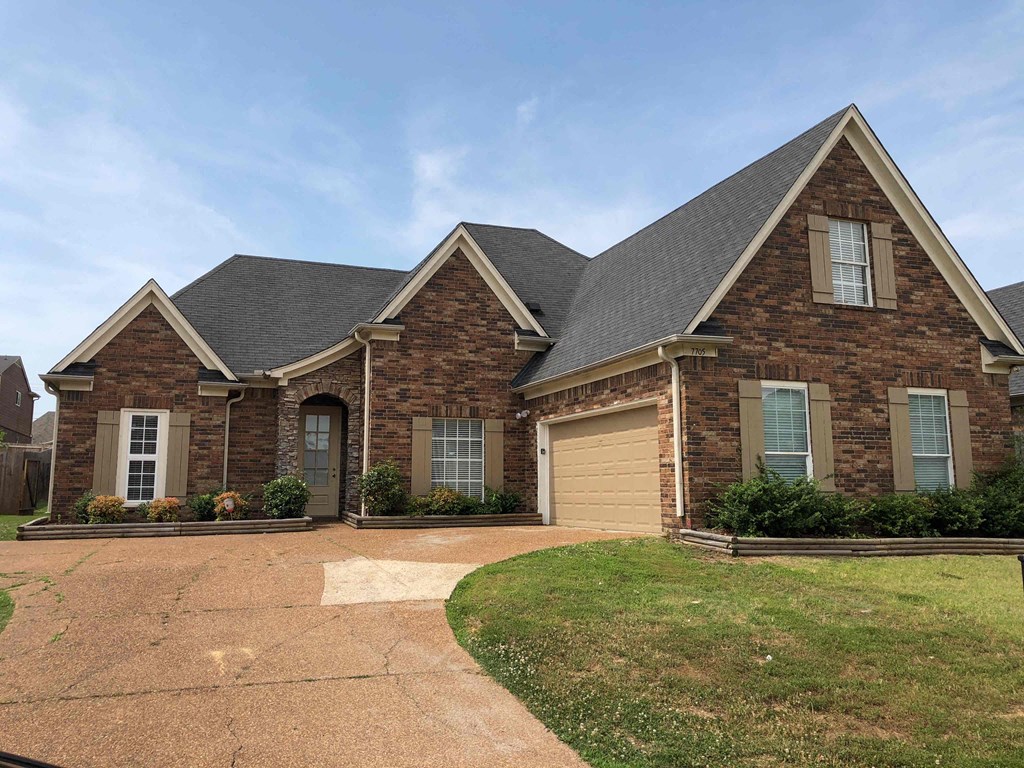 A brick house with a garage door and a driveway.