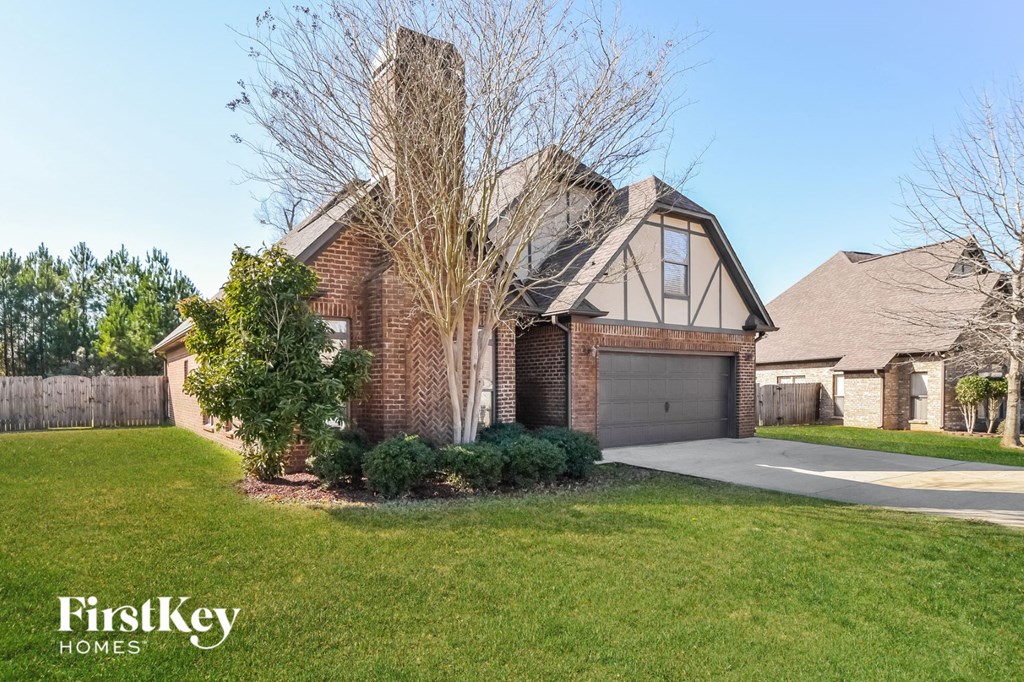 A house with a garage and a tree in front of it.