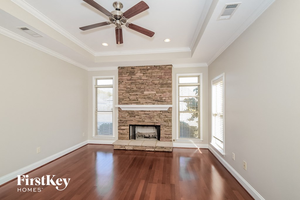 A spacious room with a fireplace and a ceiling fan.