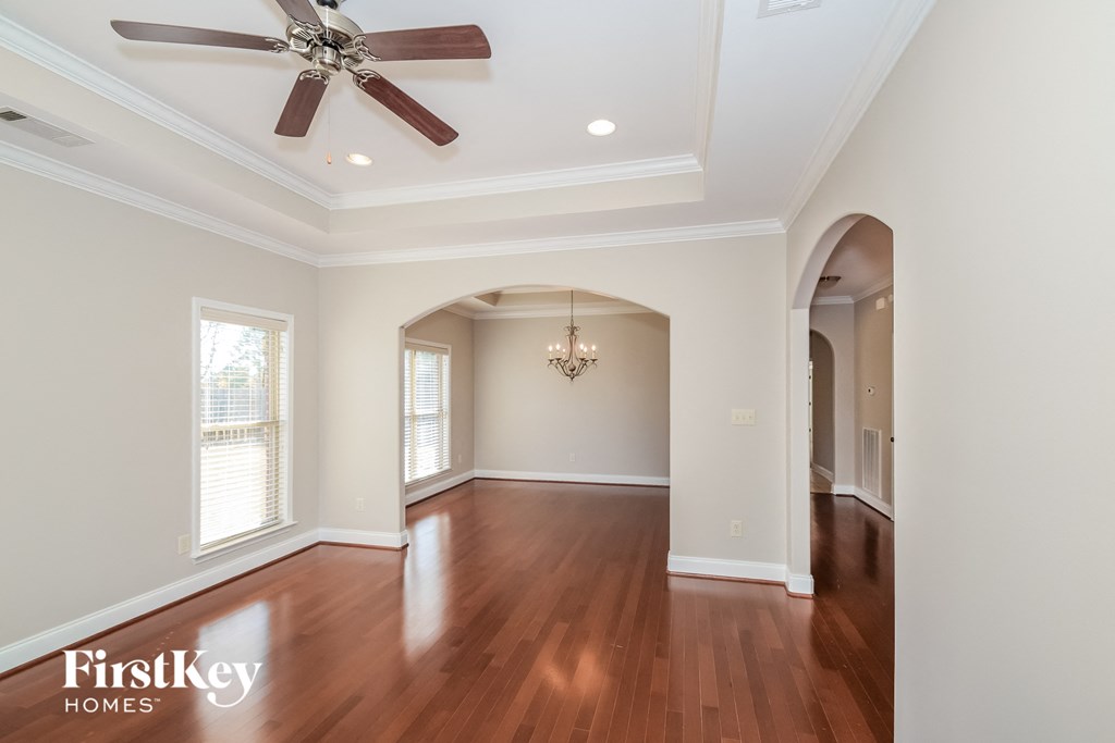 A spacious room with a ceiling fan and hardwood floors.
