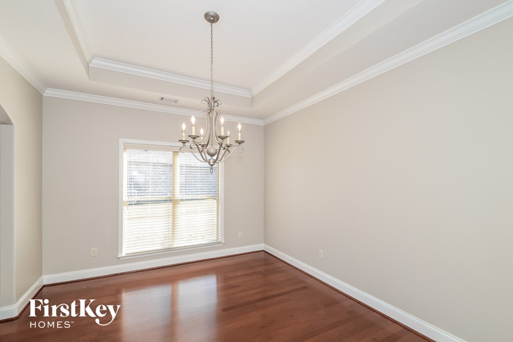 A room with a chandelier and a window with blinds.