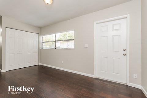 A room with a white door and a window with blinds.