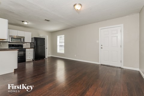 A spacious empty room with wooden floors and a white door.