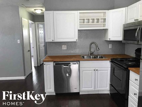 A kitchen with white cabinets and a wooden countertop.