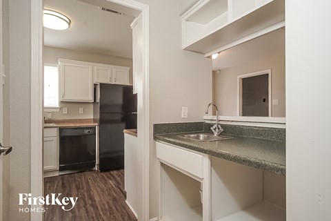 a kitchen with a sink and a black refrigerator