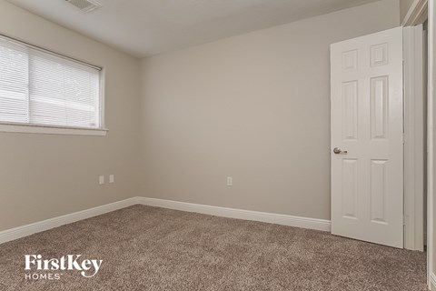the bedroom of a house with a white door and carpet
