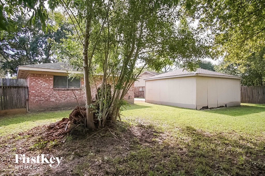 a tree in a yard in front of a brick house