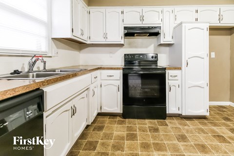 a kitchen with white cabinets and black appliances