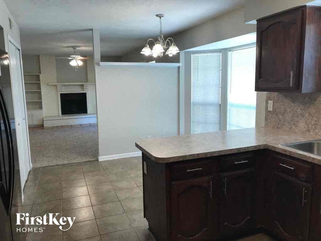A kitchen with dark wood cabinets and a granite countertop.