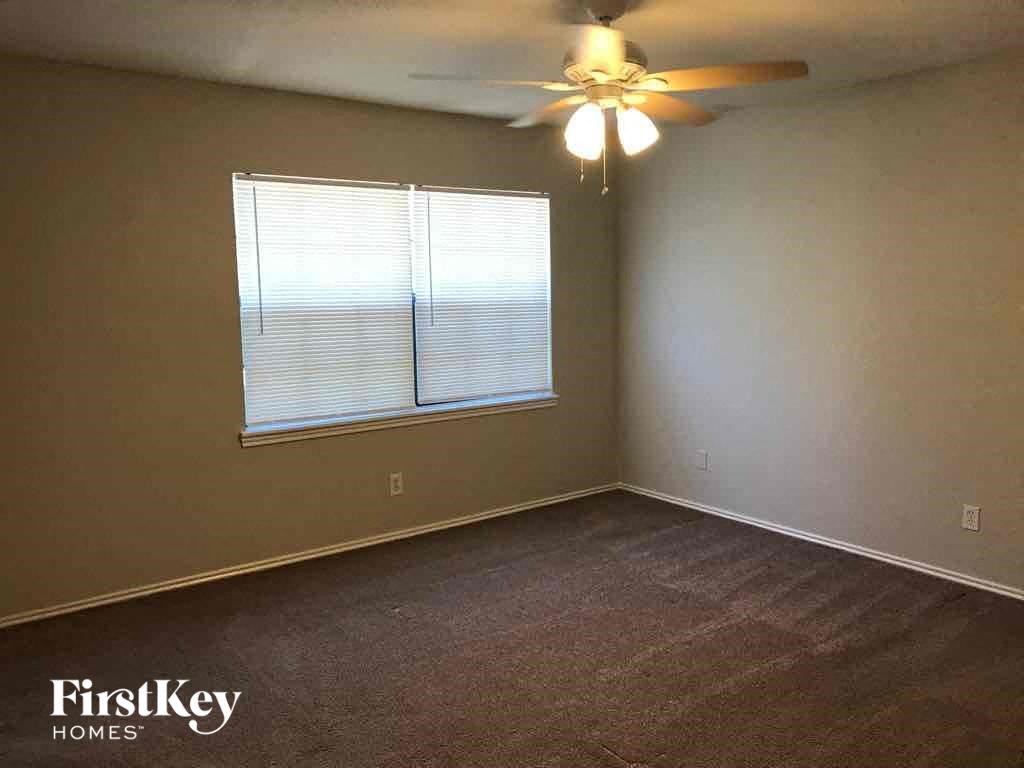 A room with a ceiling fan and a window with blinds.
