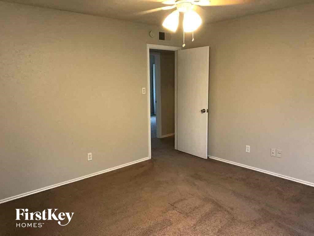 A room with a carpeted floor and a ceiling fan.