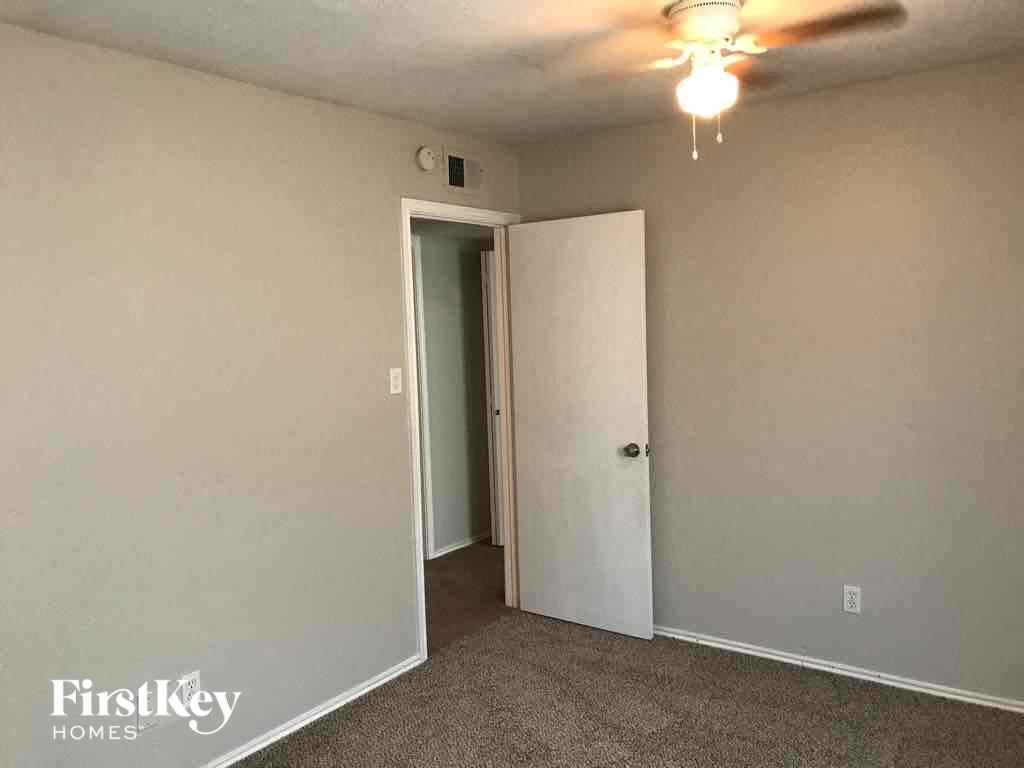 A room with a carpeted floor and a ceiling fan.