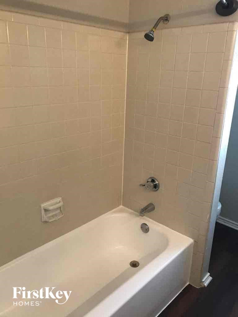 A white bathtub in a bathroom with a shower head.