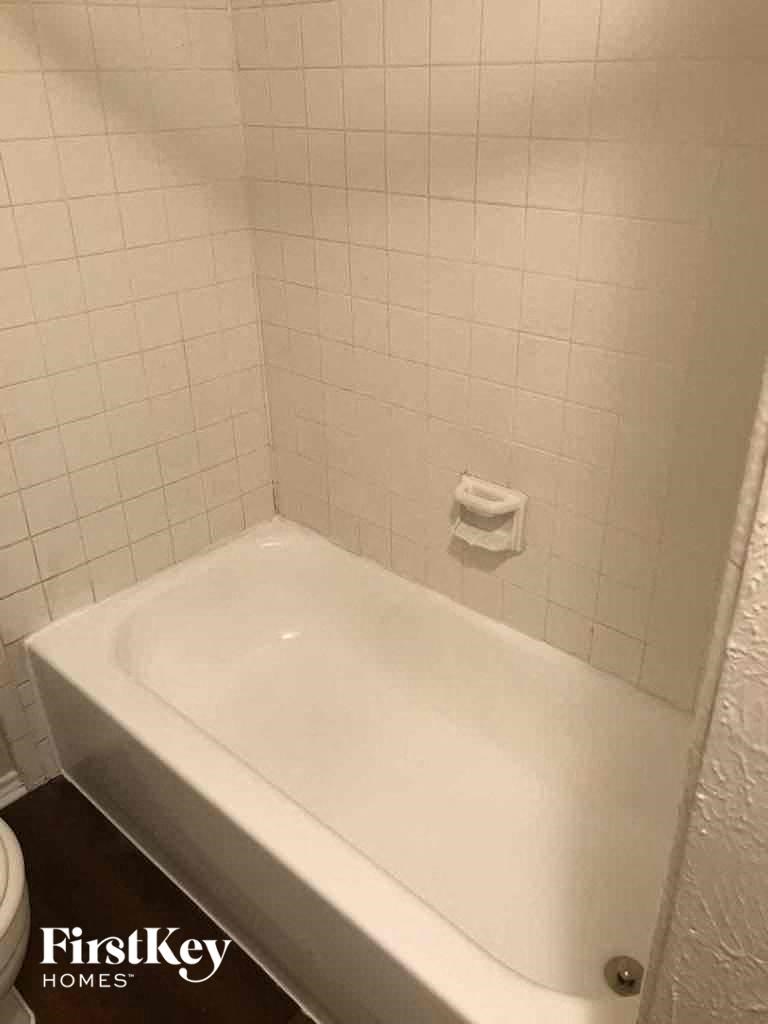 A white bathtub in a bathroom with white tiled walls.