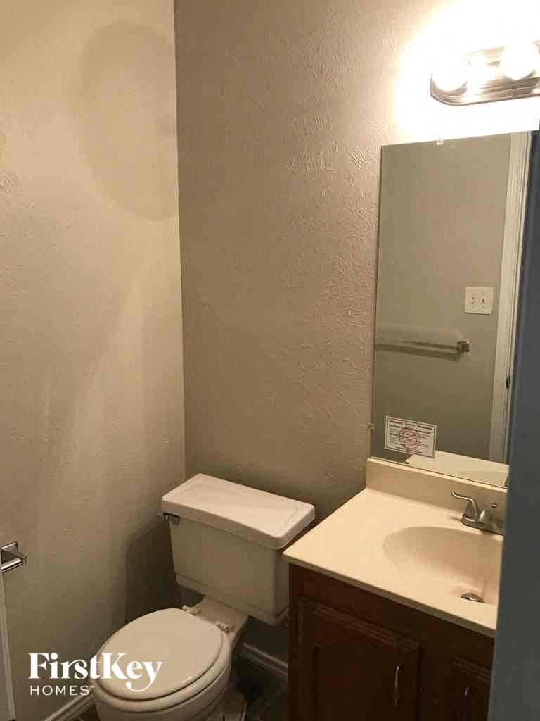 A bathroom with a toilet, sink and mirror.