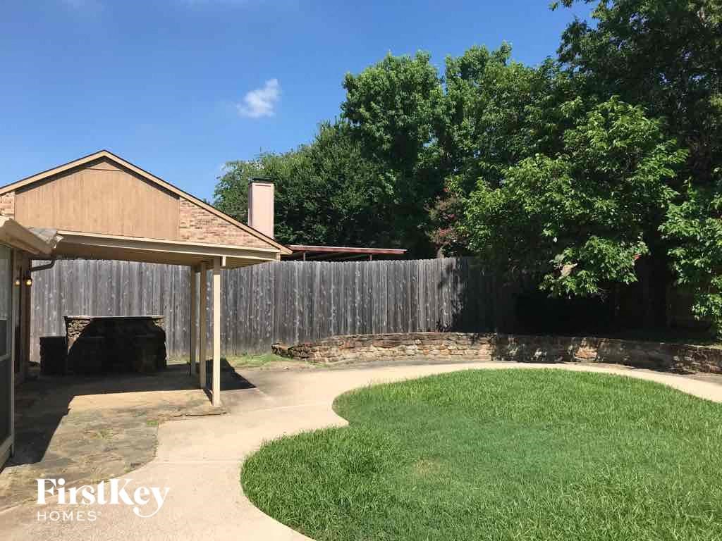 A backyard with a wooden fence and a small pavilion.
