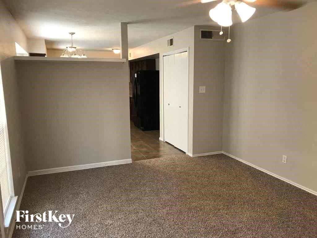 A room with a carpet floor and a black refrigerator.