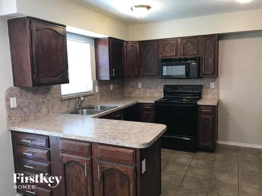 A kitchen with brown cabinets and a black oven.