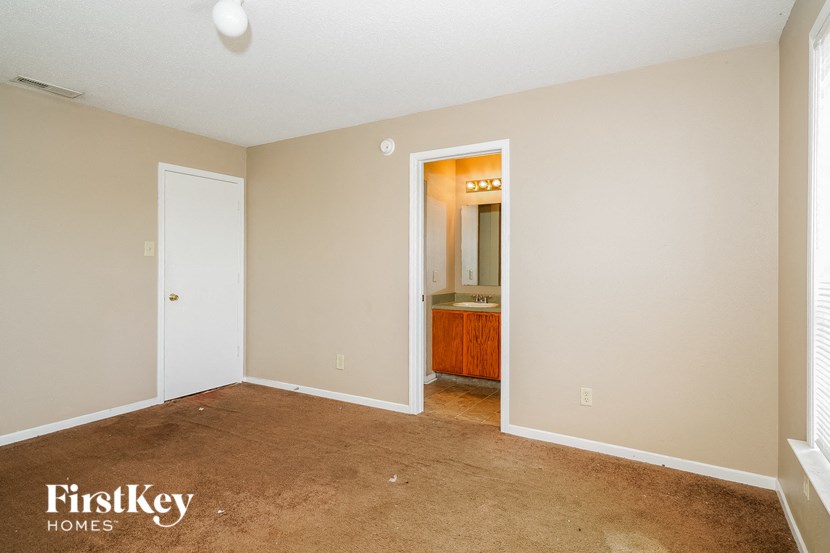 an empty living room with a bathroom in the background