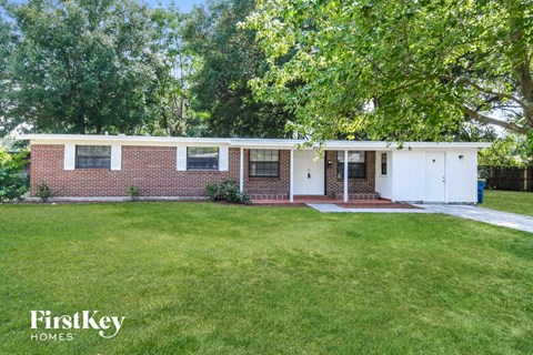 a white and brick house with a lawn and trees