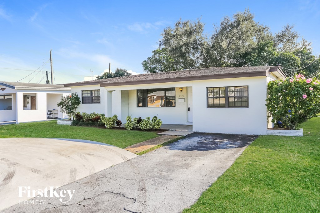 a white house with a driveway and a lawn