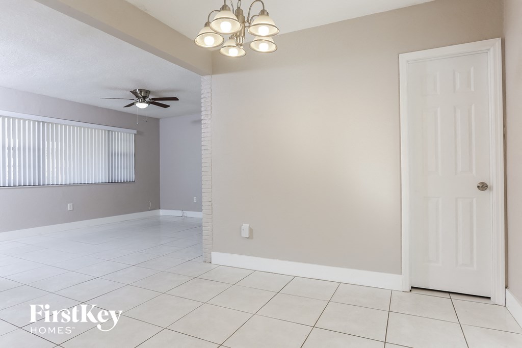 an empty living room with a ceiling fan and a white door