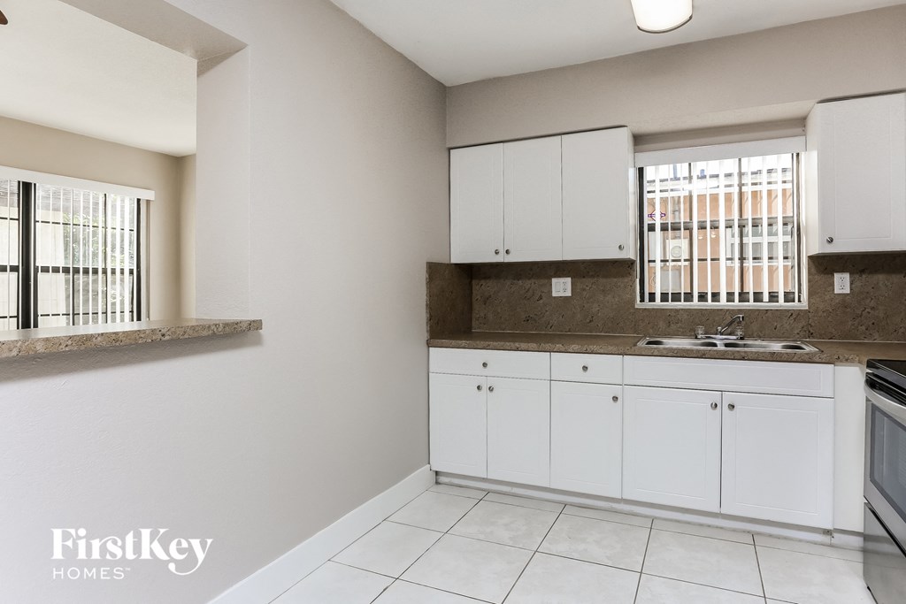 a kitchen with white cabinets and a sink and a window