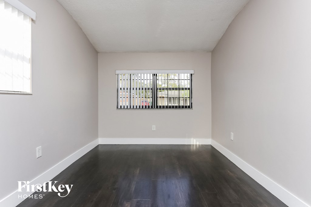 an empty living room with wood floors and a window