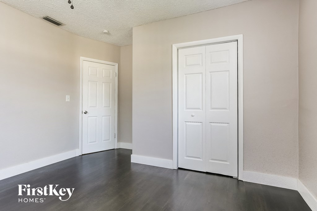 the living room of an apartment with white doors and grey flooring