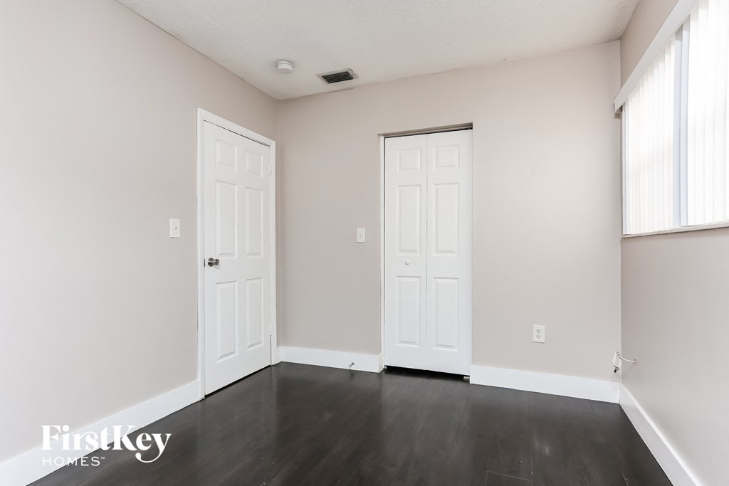 a living room with two doors and a dark wood floor
