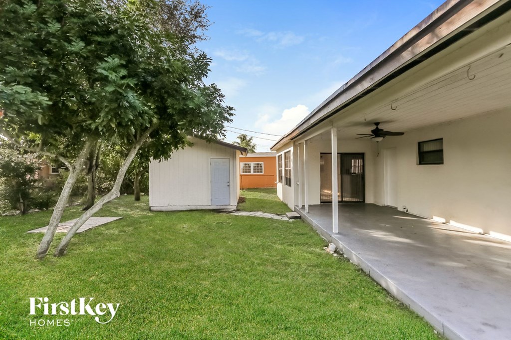 the backyard of a white house with a yard and a tree