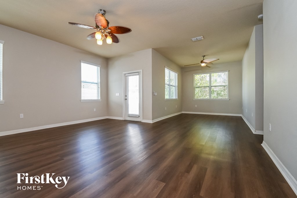A spacious room with wooden floors and two ceiling fans.