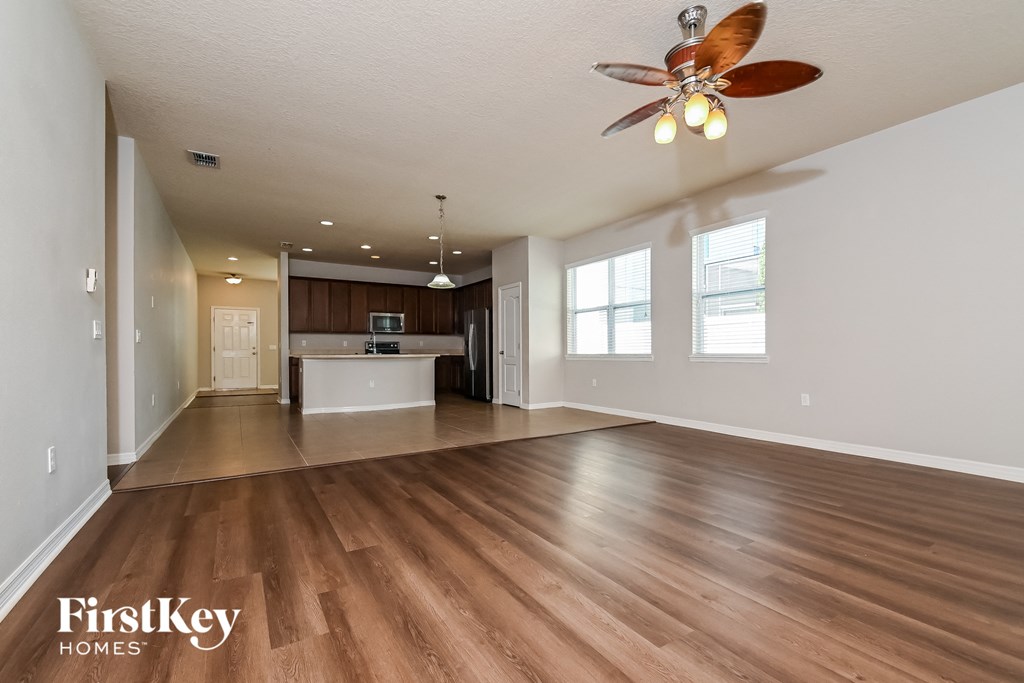 A spacious room with a ceiling fan and wooden flooring.