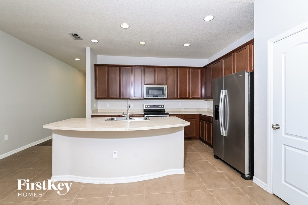 A kitchen with a white island and a refrigerator.