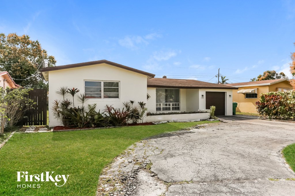 a small white house with a driveway and a lawn