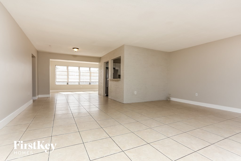an empty living room with tiled flooring and a wall with a window