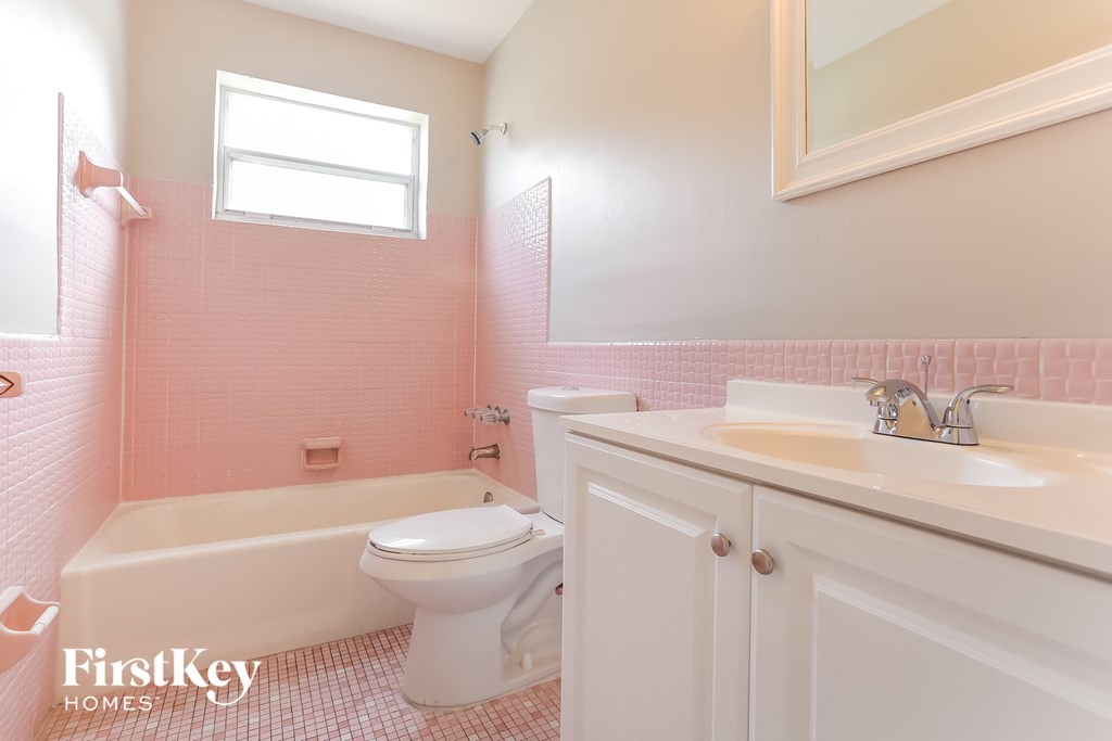 a pink bathroom with a toilet sink and tub