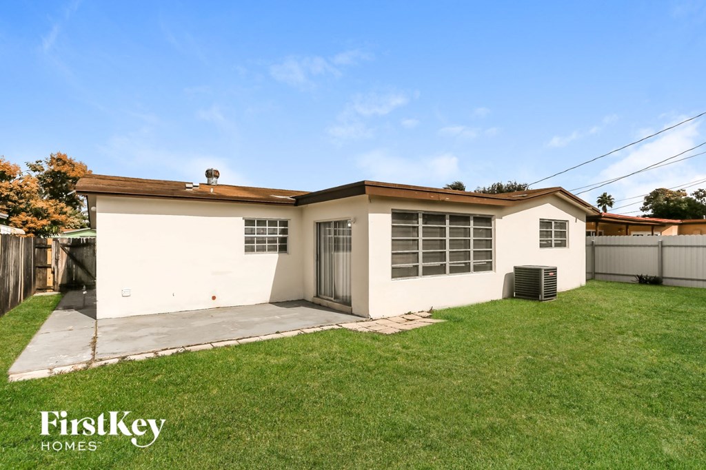 a small white house with a yard and a driveway