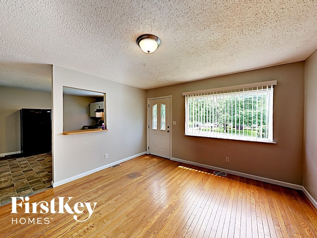 A room with wooden floors and a window with blinds.