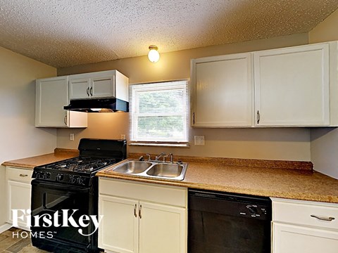 A kitchen with a black stove top oven and white cabinets.