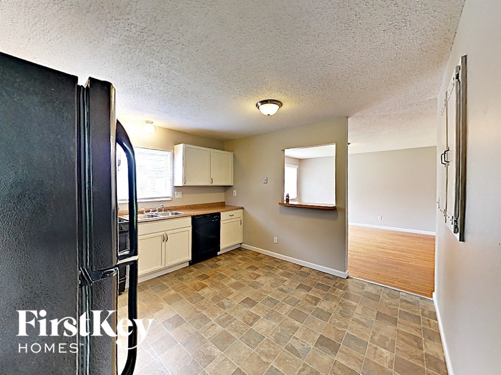 A kitchen with a black fridge and a tile floor.