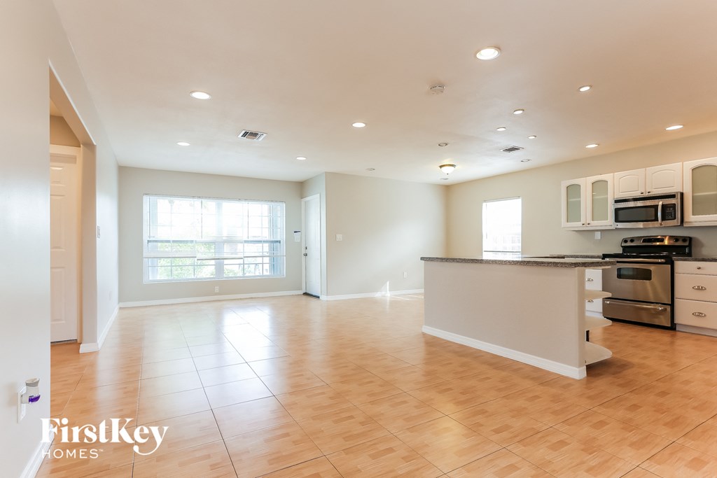 an open kitchen and living room with wood floors and white cabinets