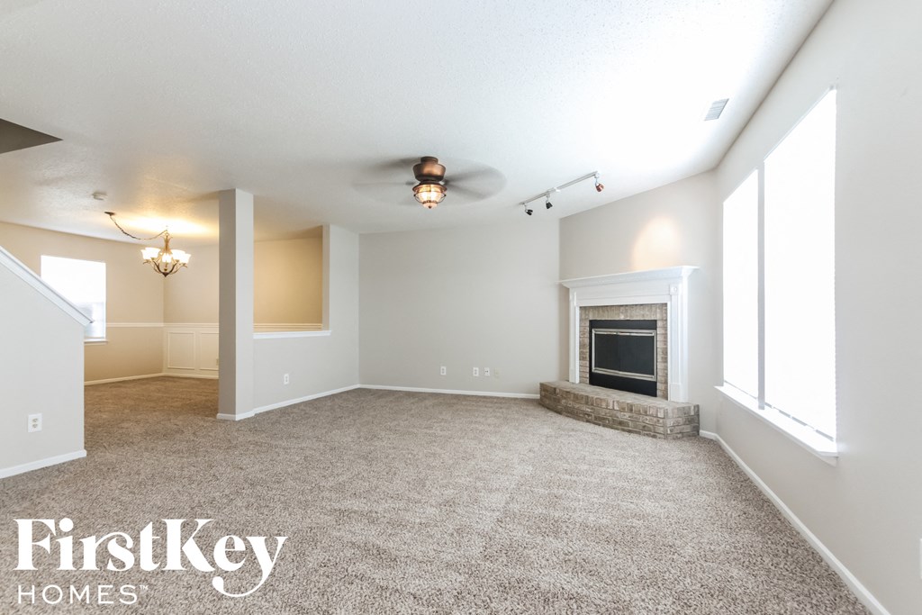 a spacious living room with a fireplace and carpeted flooring