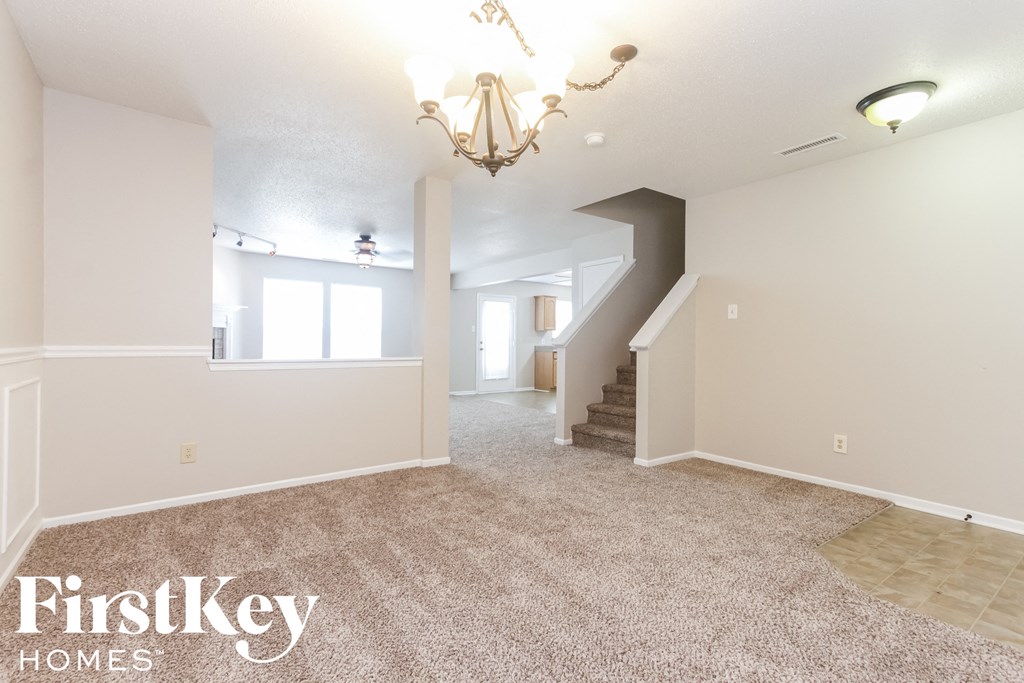 the upstairs living room and dining room with carpeting and a chandelier