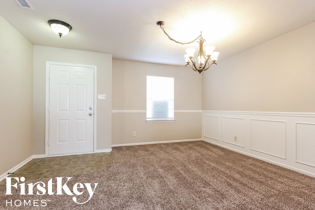 an empty dining room with carpet and a chandelier