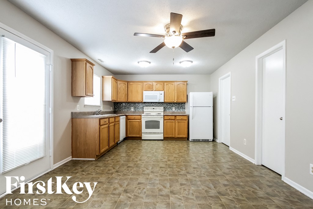 an empty kitchen with wooden cabinets and a ceiling fan