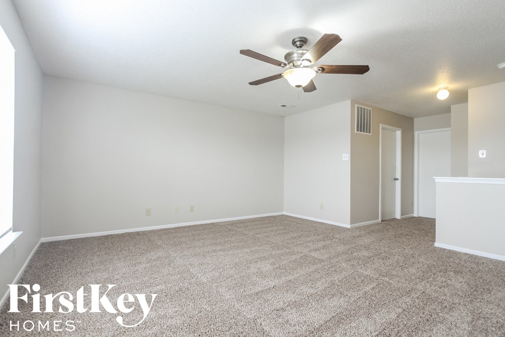 the spacious living room with ceiling fan and carpeting