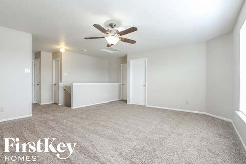 a spacious living room with carpet and a ceiling fan