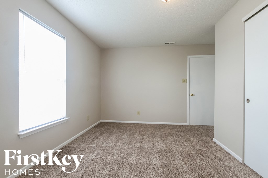 a bedroom with carpet and white walls and a window