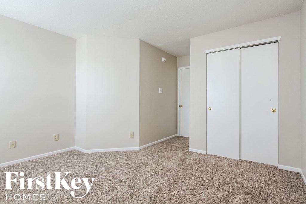 a bedroom with white walls and carpet and white closet doors